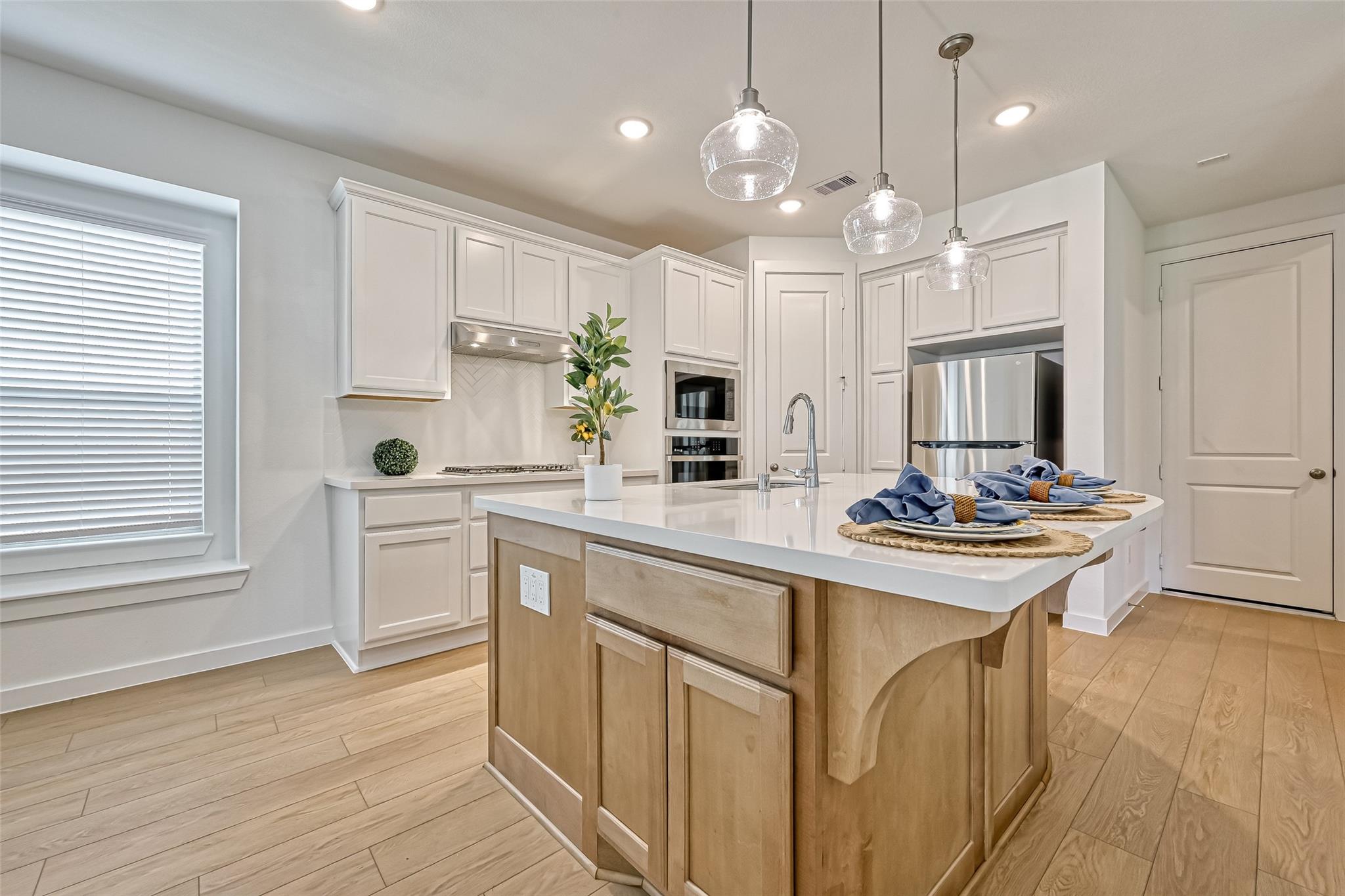 Kitchen with a large wood-paneled island, white cabinetry, and stainless steel appliances.