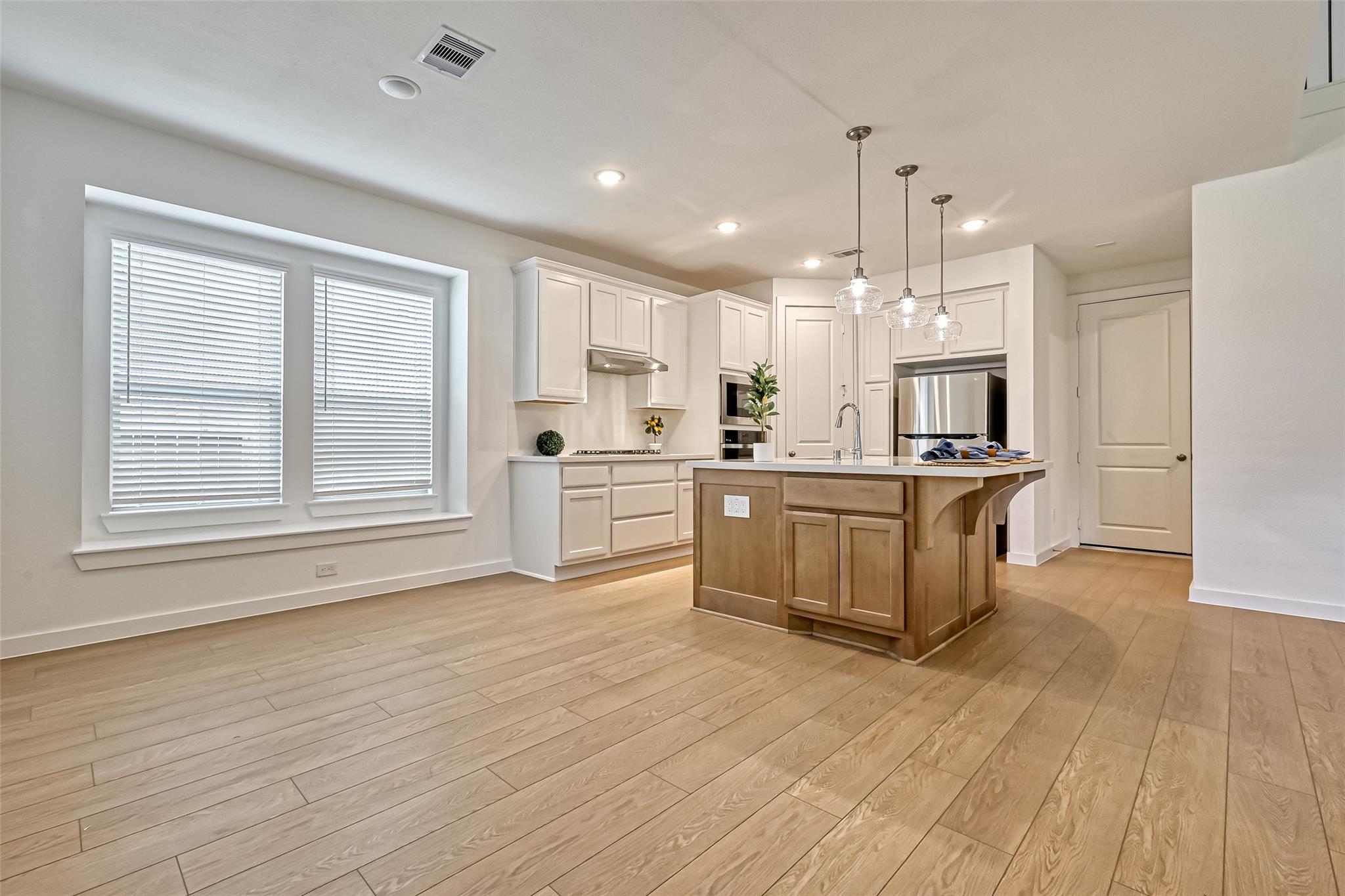 Bright kitchen with white cabinets, stainless steel appliances, and a large wood-paneled island.