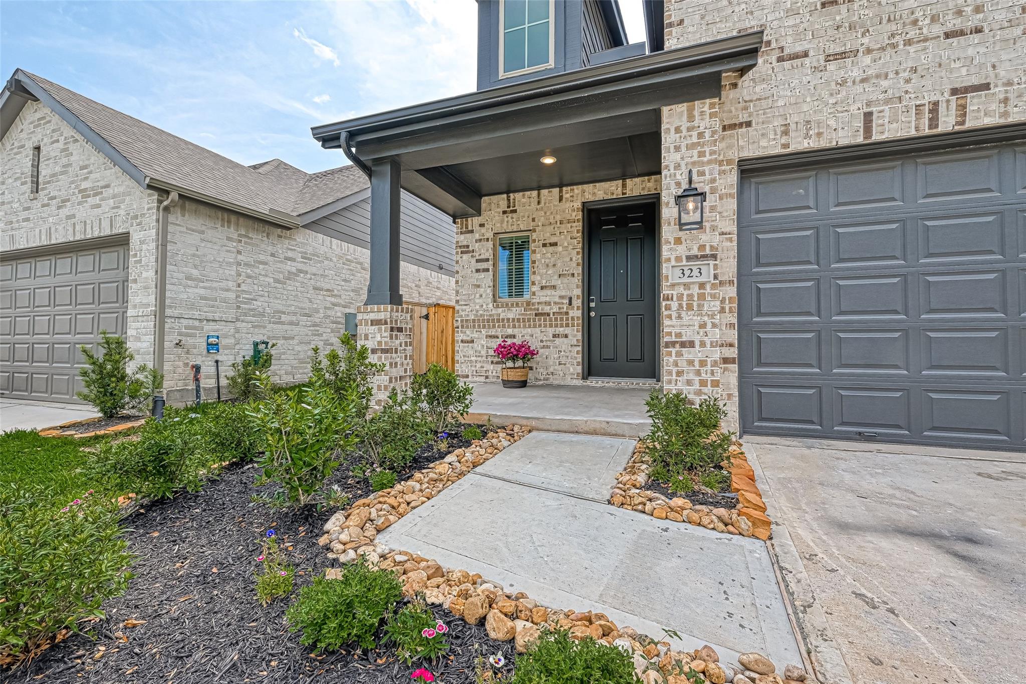 Brick home exterior with a covered entry, dark garage doors, and landscaped walkway.