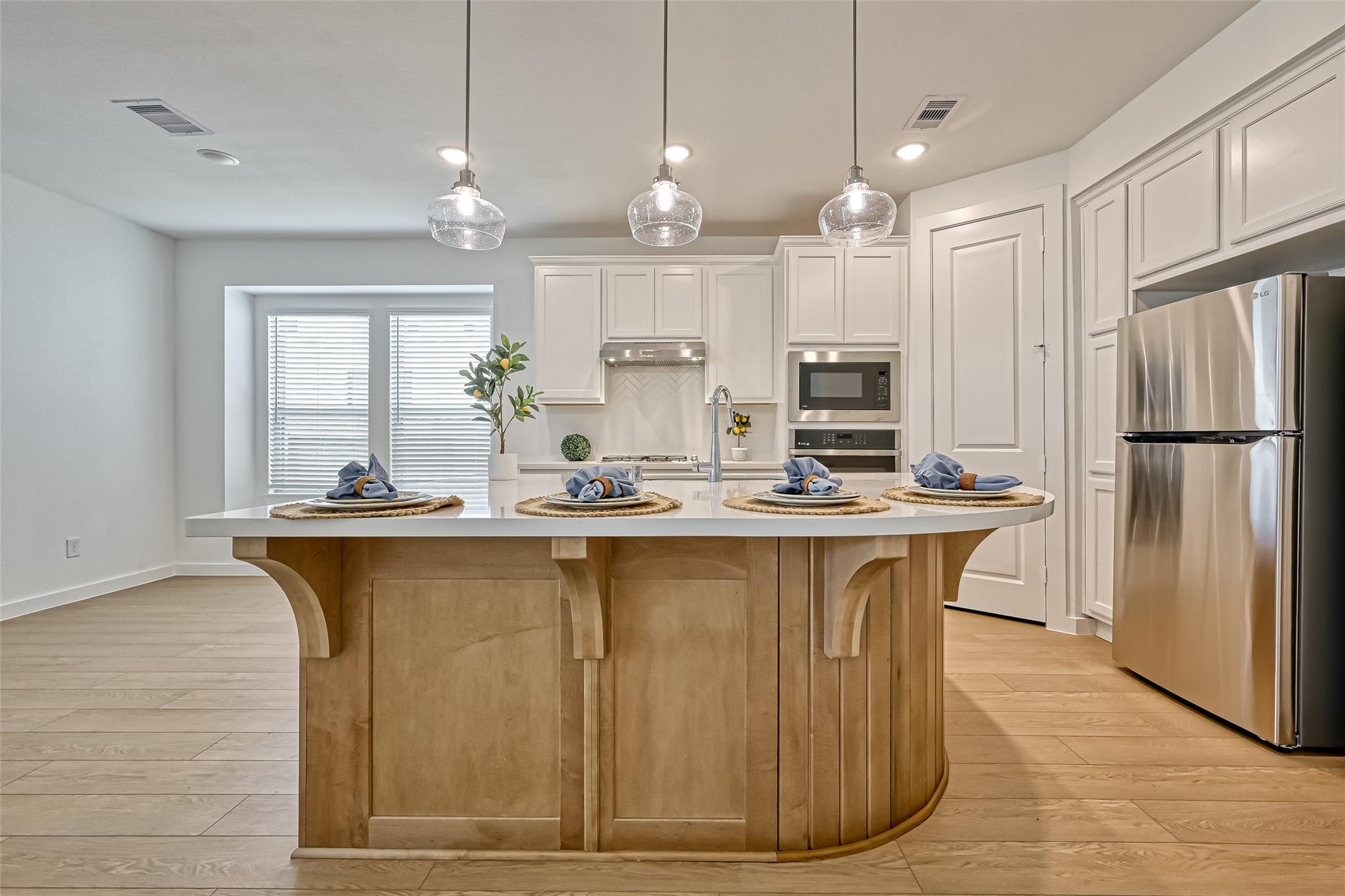Kitchen with a curved wood island, white cabinetry, and stainless steel appliances.