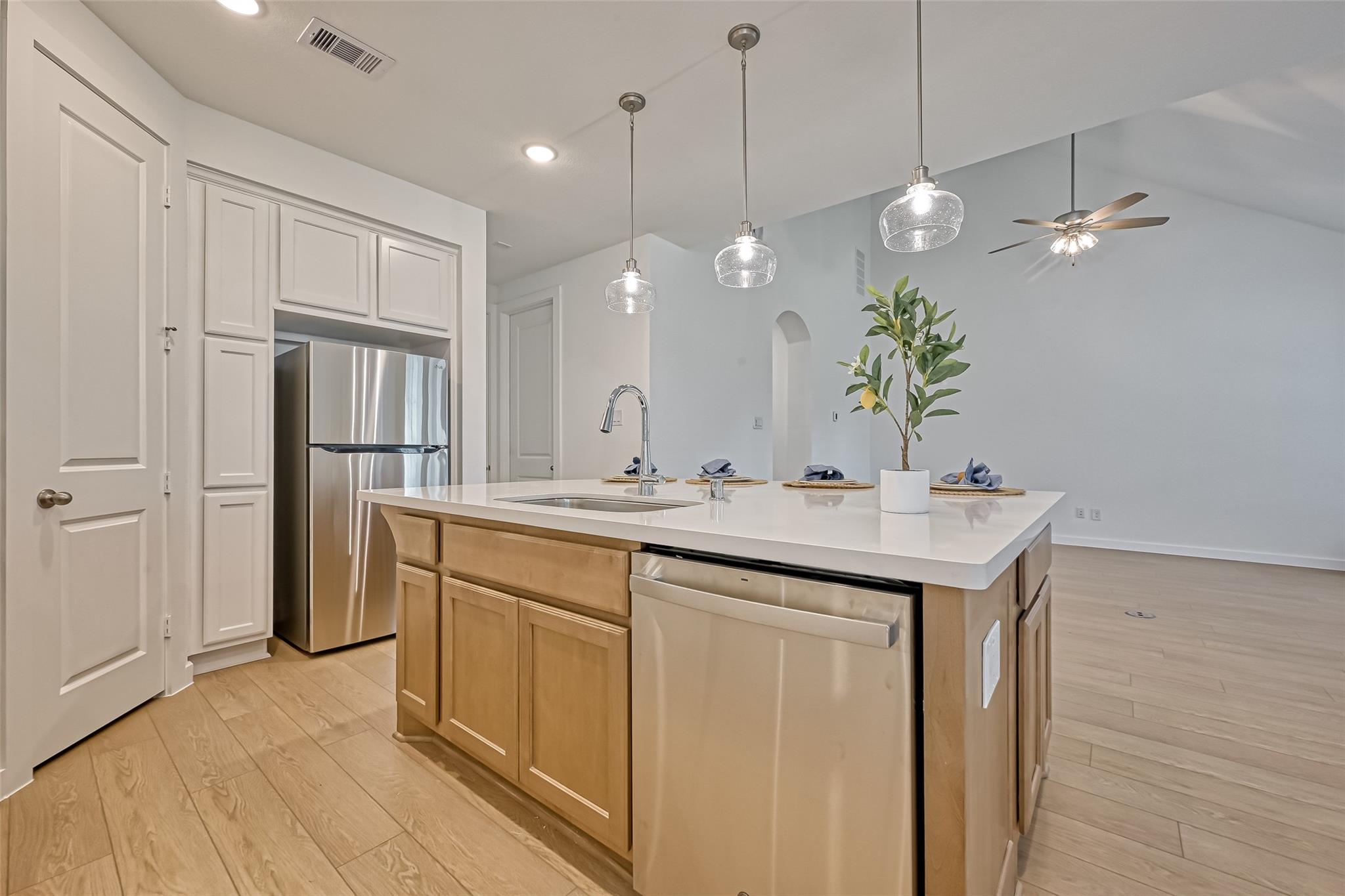 Kitchen with a large wood island, white countertop, stainless appliances, and glass pendant lights.