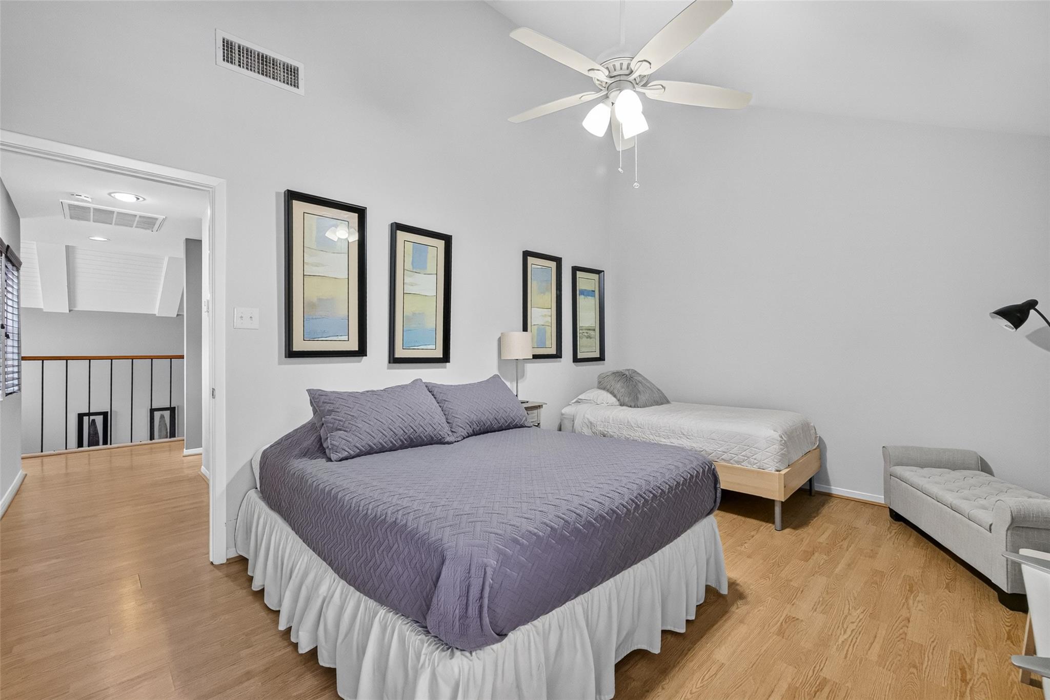 Bedroom with a lavender-quilted bed, a second single bed, and a ceiling fan.