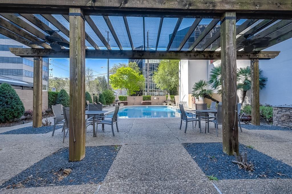 Outdoor swimming pool and patio seating beneath a wooden pergola.