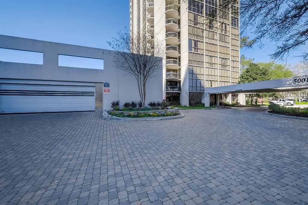 High-rise residential building entrance with a covered drop-off drive and paved circular approach.