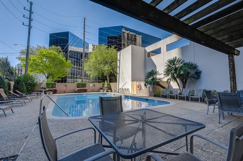 Outdoor pool courtyard with lounge chairs, palm trees, and a pergola.