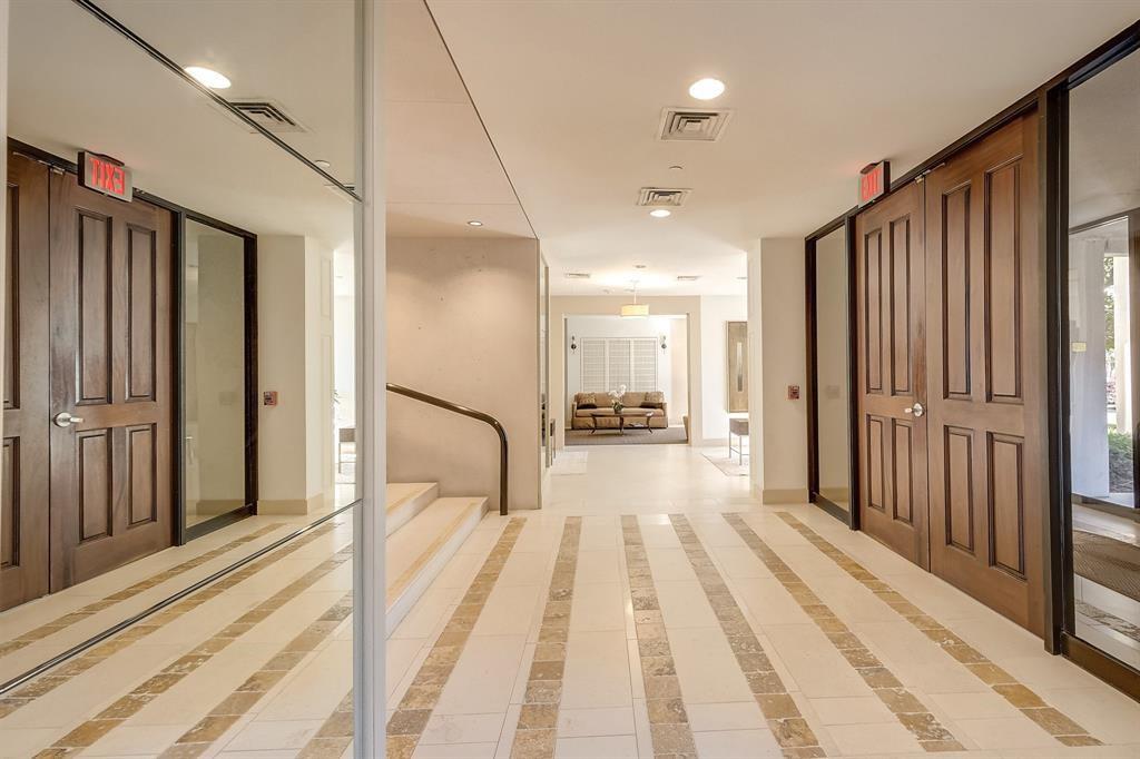 Condominium entry hall with patterned tile flooring, dark wood doors, and a large wall mirror.
