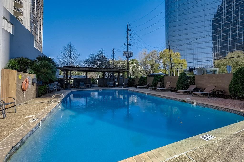 Outdoor swimming pool surrounded by lounge chairs and high-rise buildings.