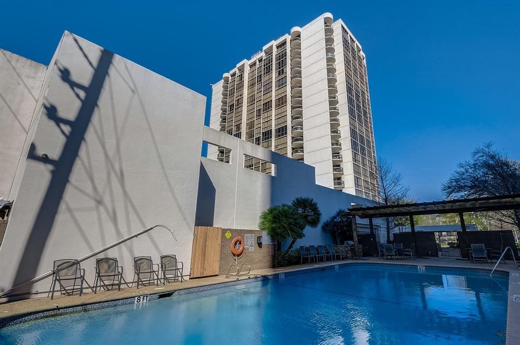 Condominium pool with lounge chairs and a covered seating area beneath the high-rise tower.