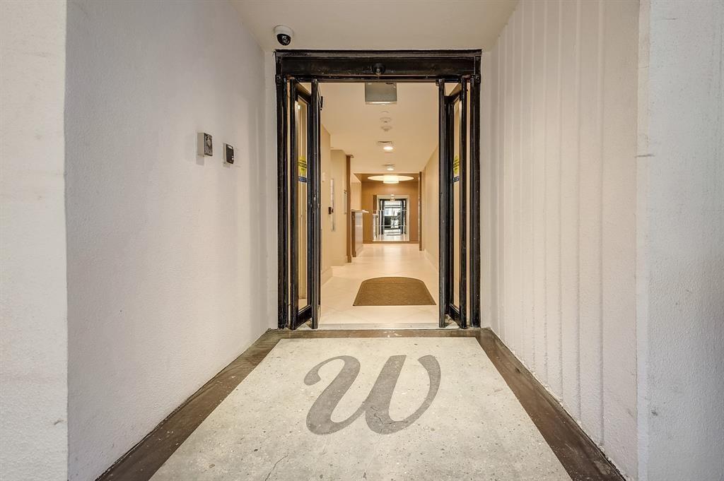 Condominium elevator entrance opening onto a bright hallway, with a large W set into the floor.