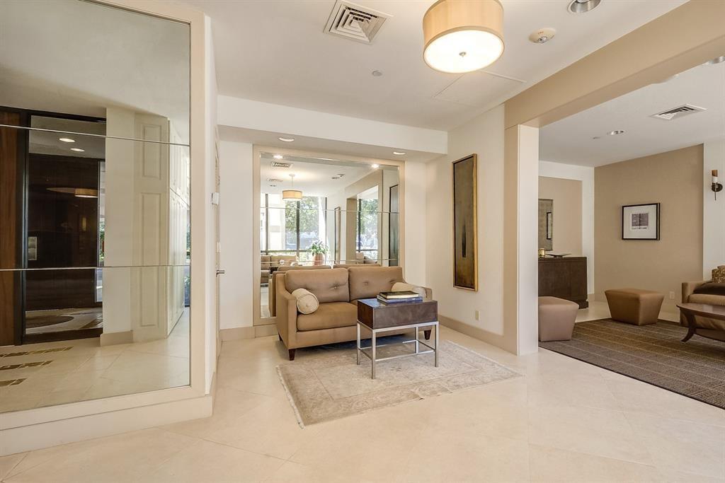 Living room with a beige sofa, coffee table, large mirror, and adjoining sitting area.