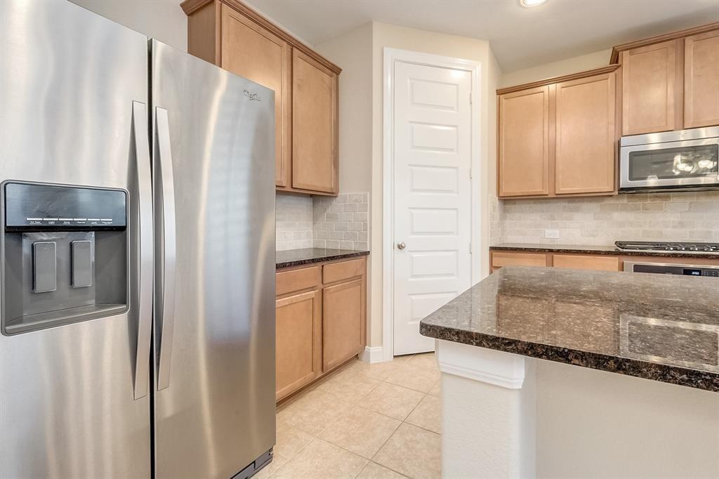 Kitchen with stainless steel appliances, wood cabinets, and a large granite island.