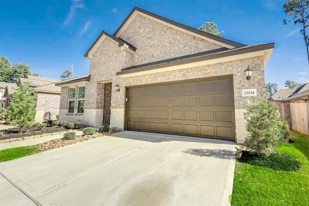 Brick home with a two-car garage, wide driveway, landscaped beds, and house number 22614.