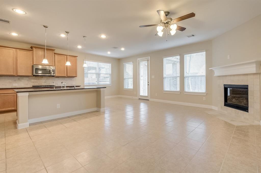 Open-plan kitchen and living area with tile flooring, wood cabinets, and a fireplace.