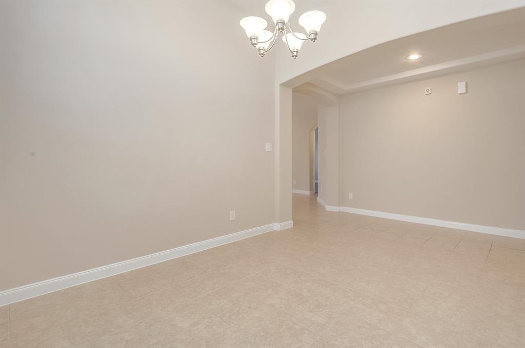 Empty dining room with tile flooring, a chandelier, and a wide arched opening.