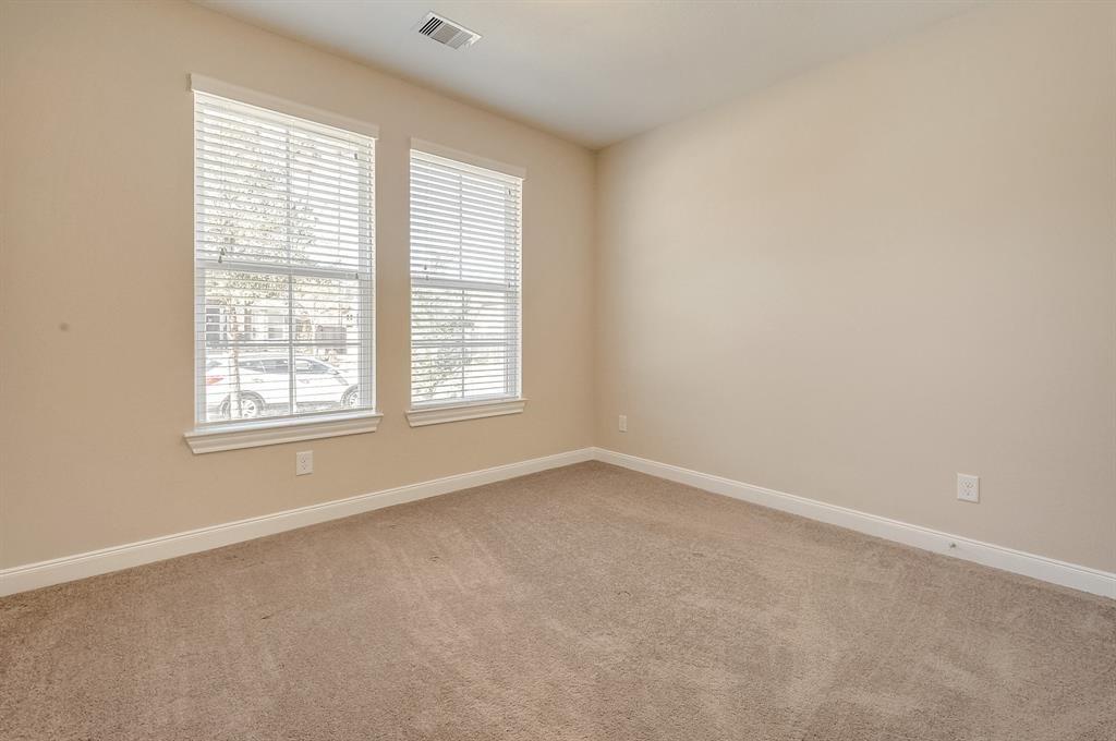 Empty carpeted room with two tall windows and white blinds.