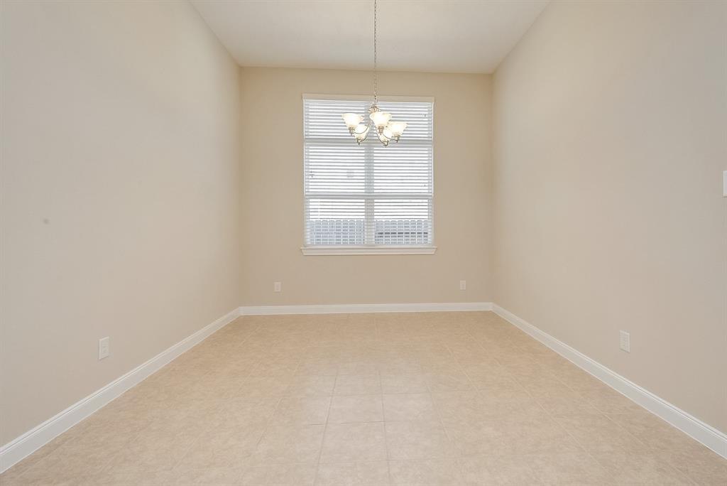 Vacant dining room with tile flooring, a chandelier, and a window with blinds.