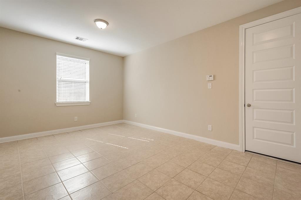 Empty beige room with a tiled floor, window blinds, and a white paneled door.