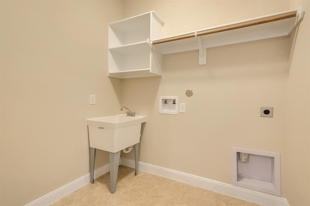 Laundry room with a utility sink, washer and dryer hookups, and a wall shelf with hanging rod.