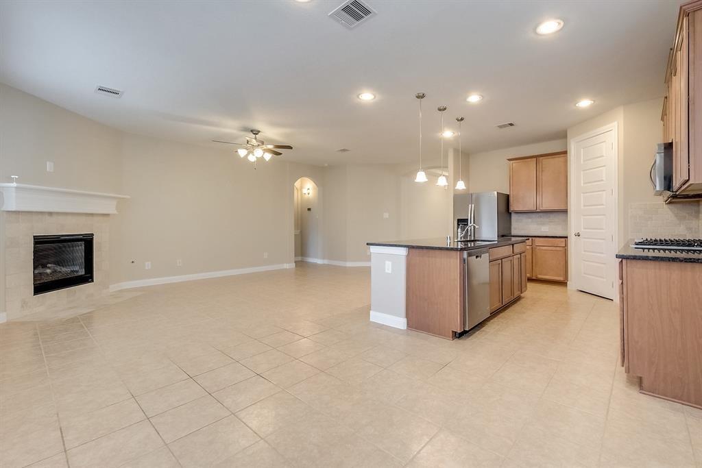 Open kitchen and living area with a central island, tile floors, and a fireplace.