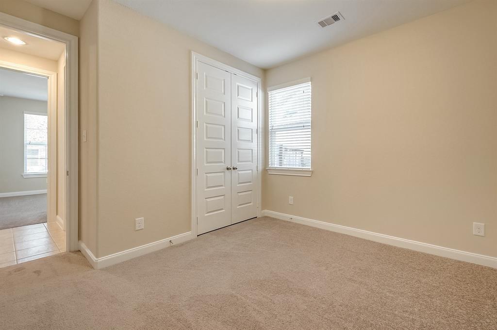 Empty carpeted bedroom with white double closet doors and a window with blinds.