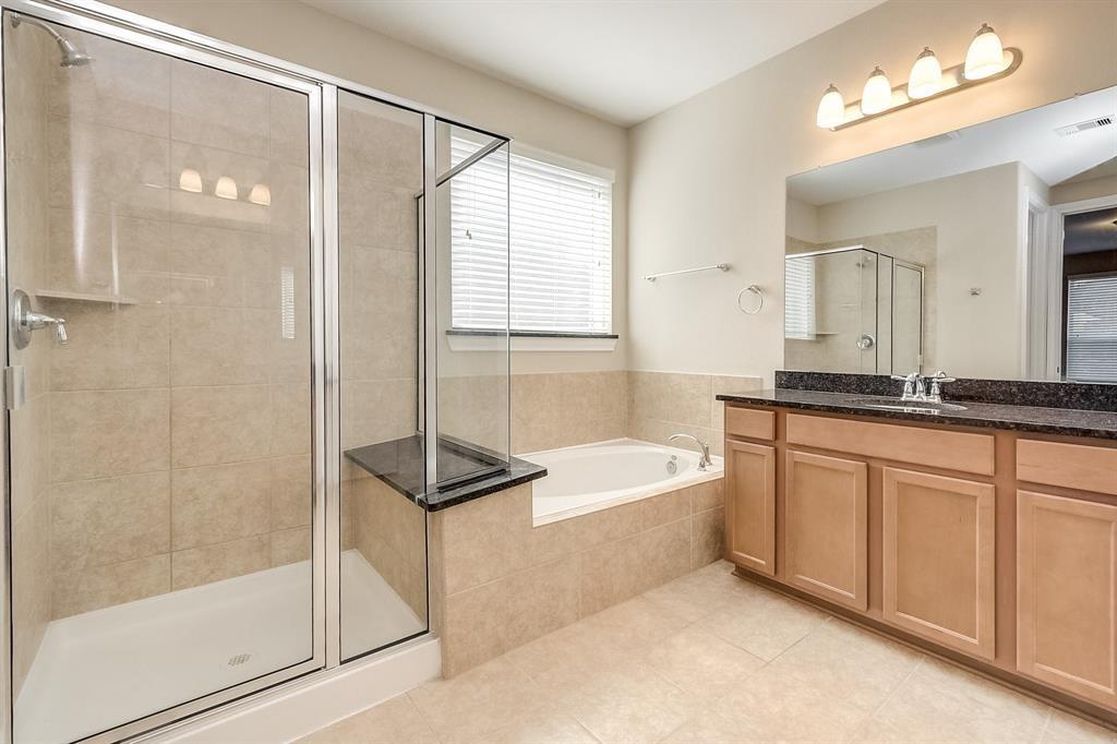 Bathroom with a glass shower, built-in tub, and long wood vanity.