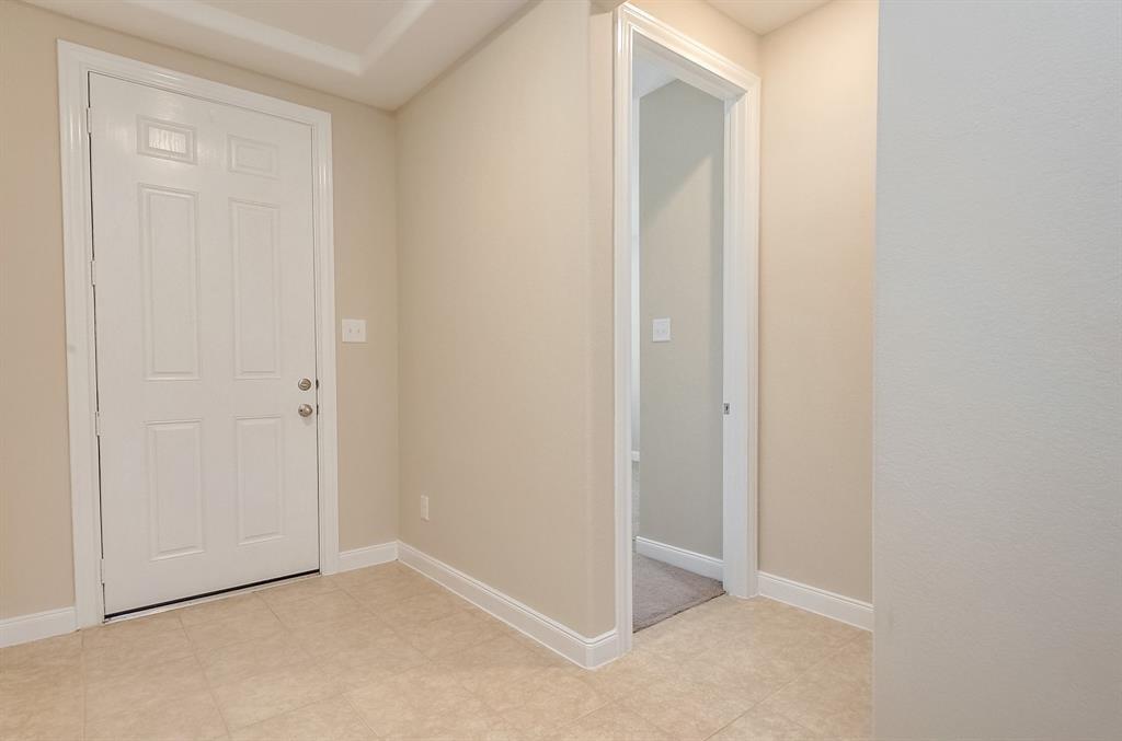 Unfurnished entryway with a white paneled front door and light tile flooring.