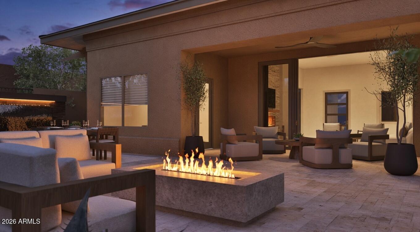 Covered patio with a long linear fire pit and cushioned seating at dusk.