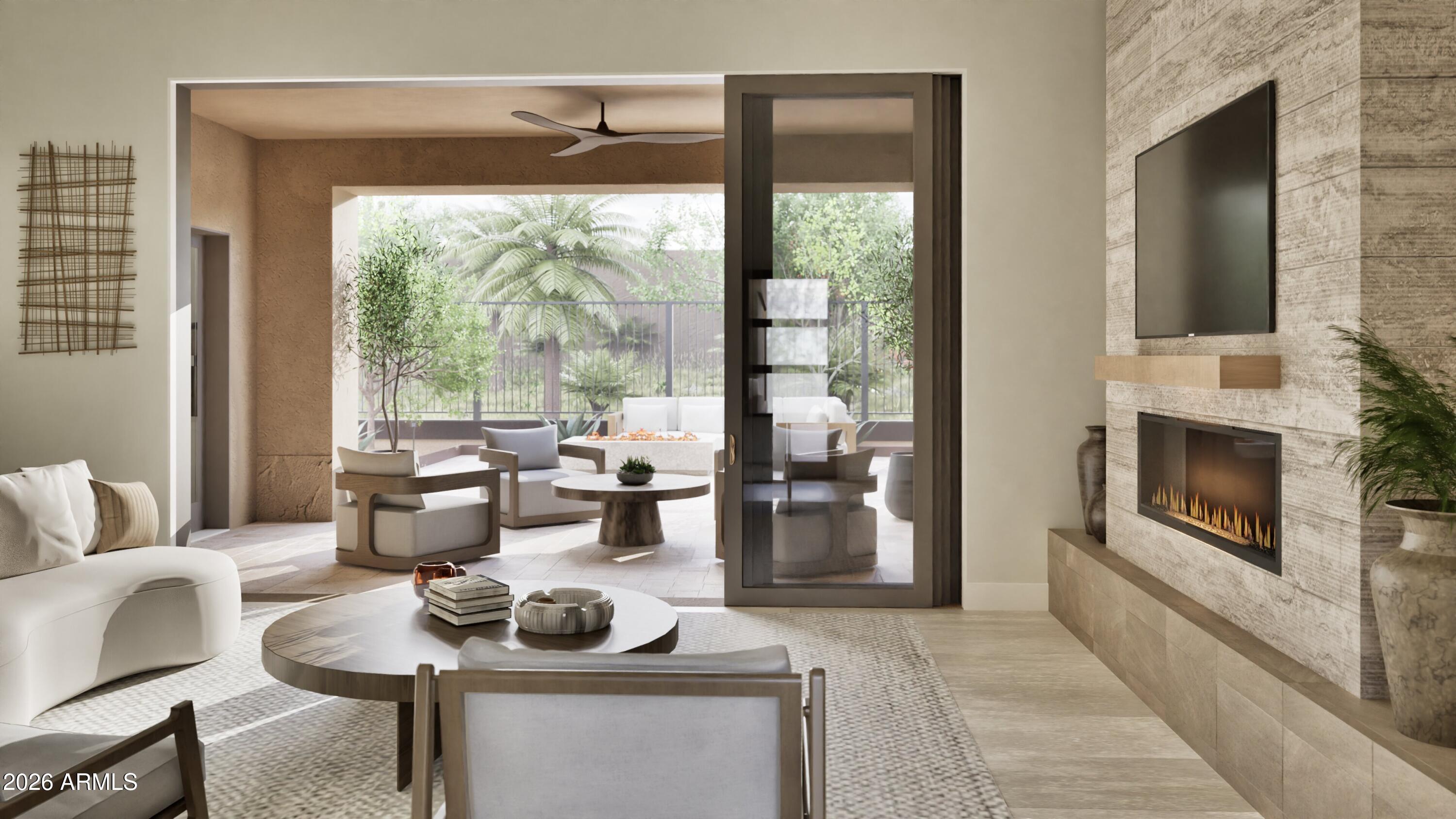 Modern living room with a stone fireplace and sliding doors opening to a furnished patio.