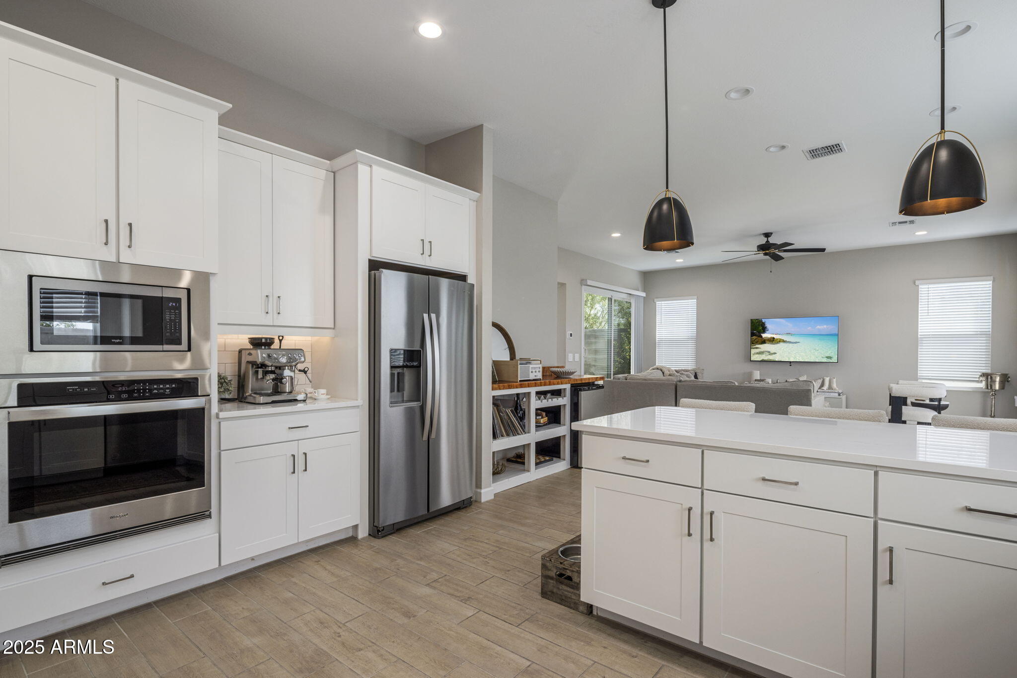 Open-plan kitchen with white cabinets, stainless steel appliances, and a large island overlooking the living room.