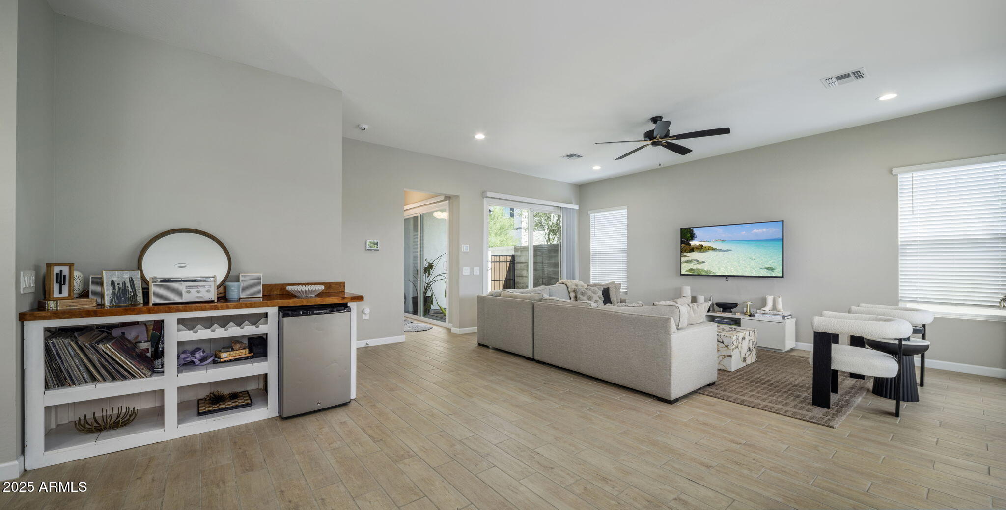 Furnished living room with a built-in bar, sliding glass doors, and ceiling fan.