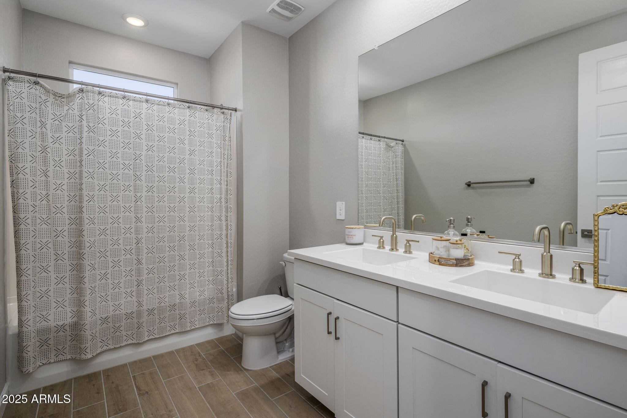 Bathroom with a patterned shower curtain and a long white double-sink vanity.
