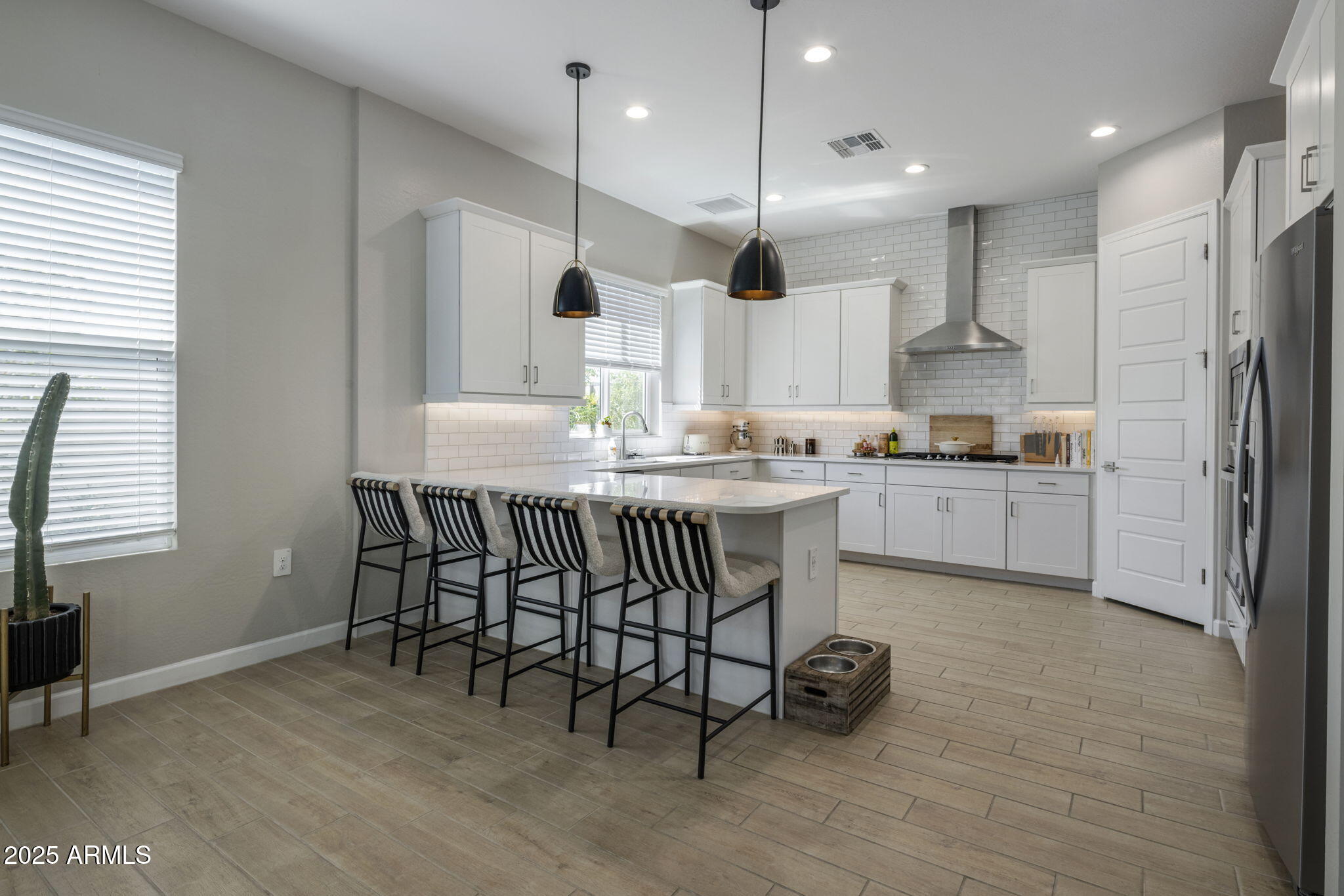 Kitchen with a large island, striped bar stools, white cabinets, and subway tile backsplash.