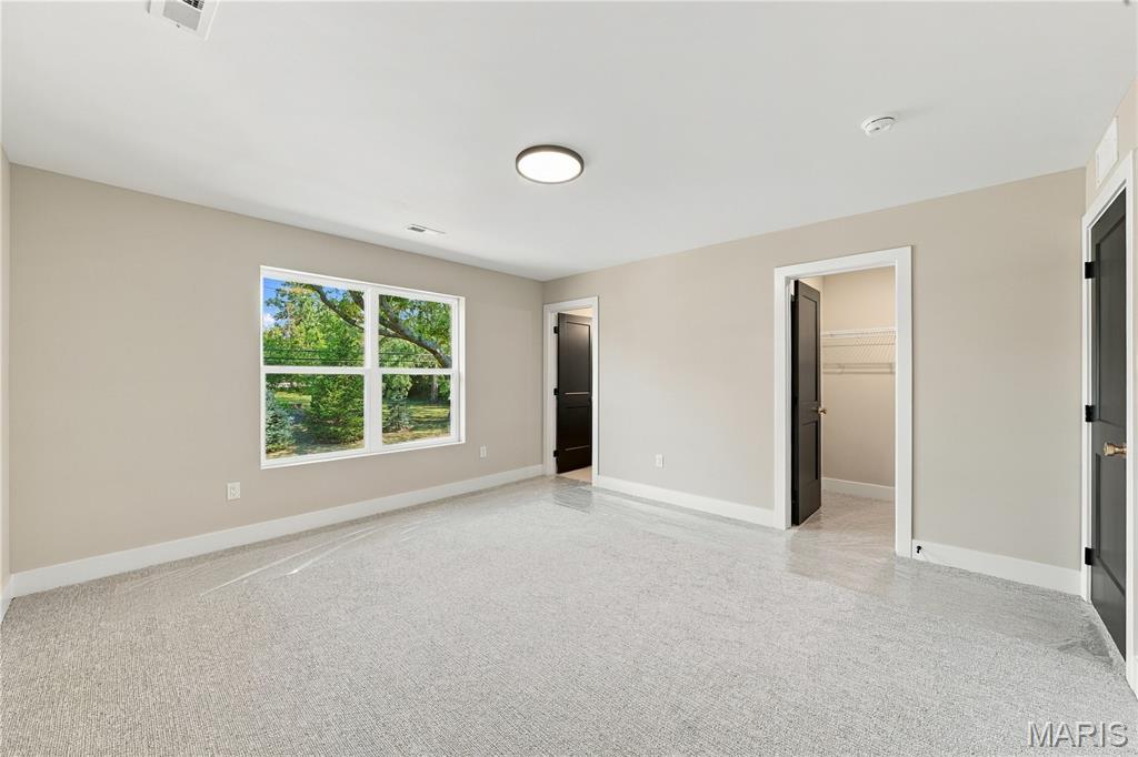 Vacant bedroom with gray carpet, a large tree-facing window, and an open closet.