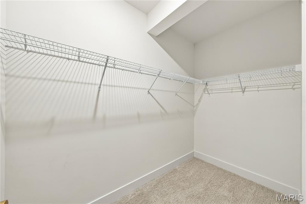 Walk-in closet with wire shelving wrapping around two walls and beige carpet.