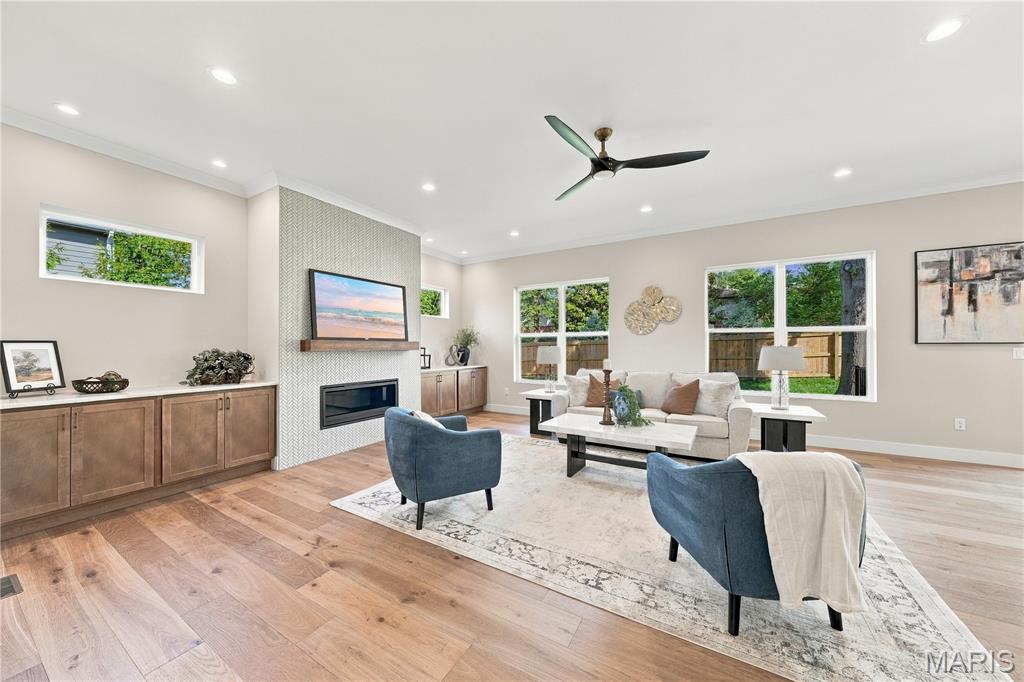 Living room with a fireplace, built-in cabinets, large windows, and blue accent chairs.