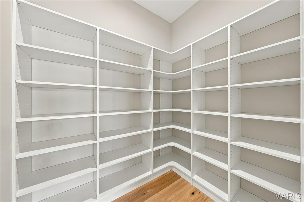 Walk-in closet with wraparound white built-in shelves and a wood floor.