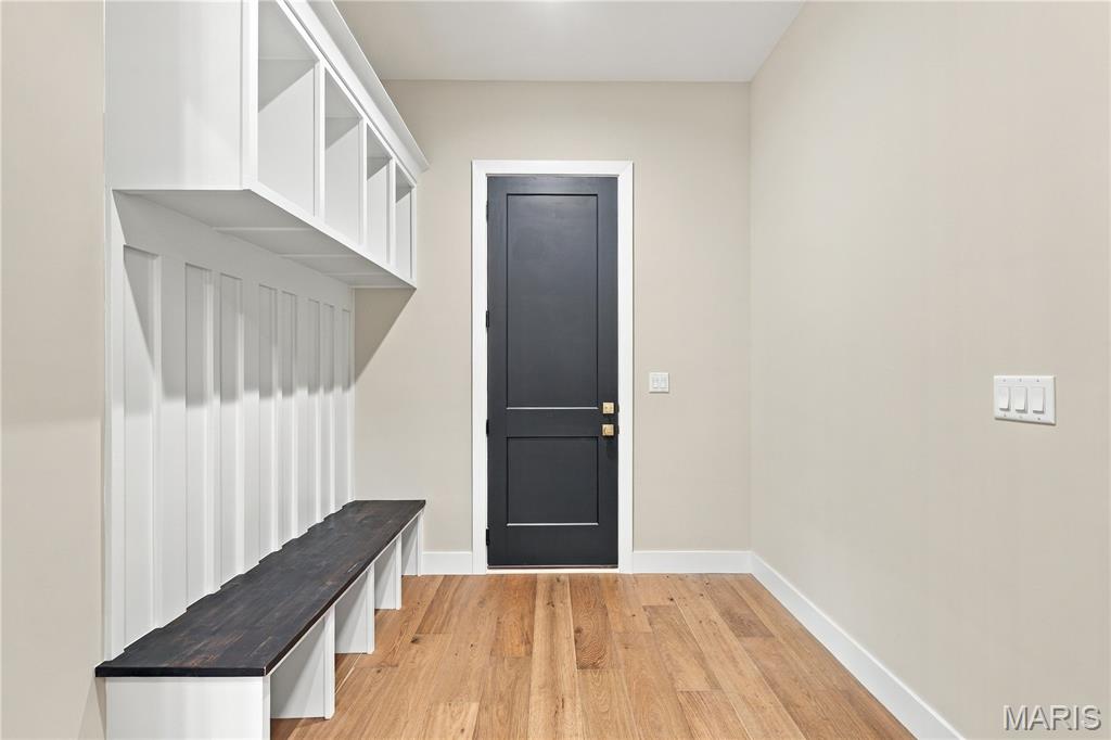 Mudroom with built-in white cubbies, a dark wood bench, and a black door.