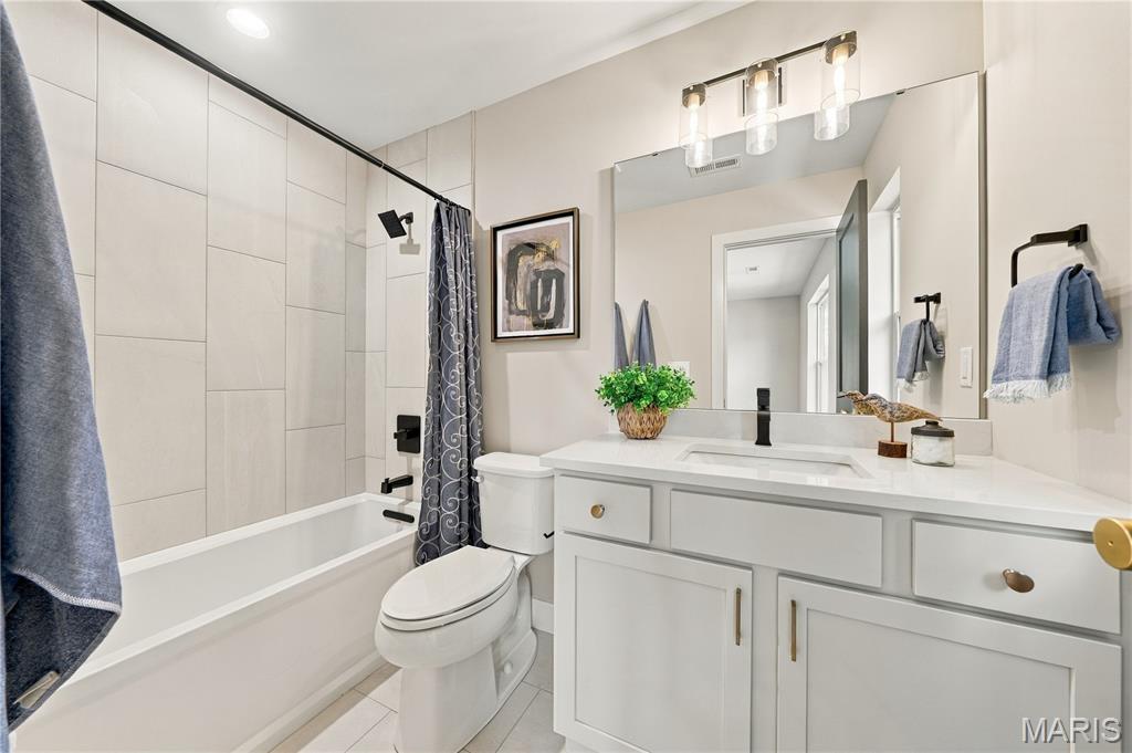 Updated bathroom with a white vanity, large mirror, and tiled tub-shower.