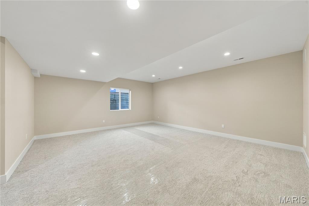 Vacant carpeted room with recessed lights and a small window.
