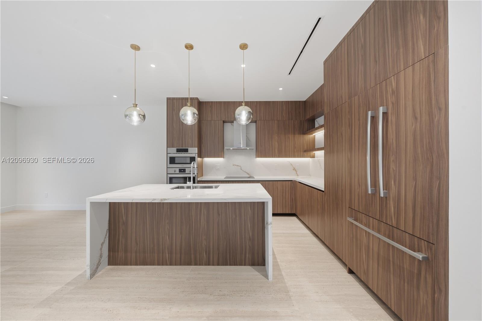 Modern kitchen with walnut cabinetry, a white stone island, and built-in stainless steel appliances.