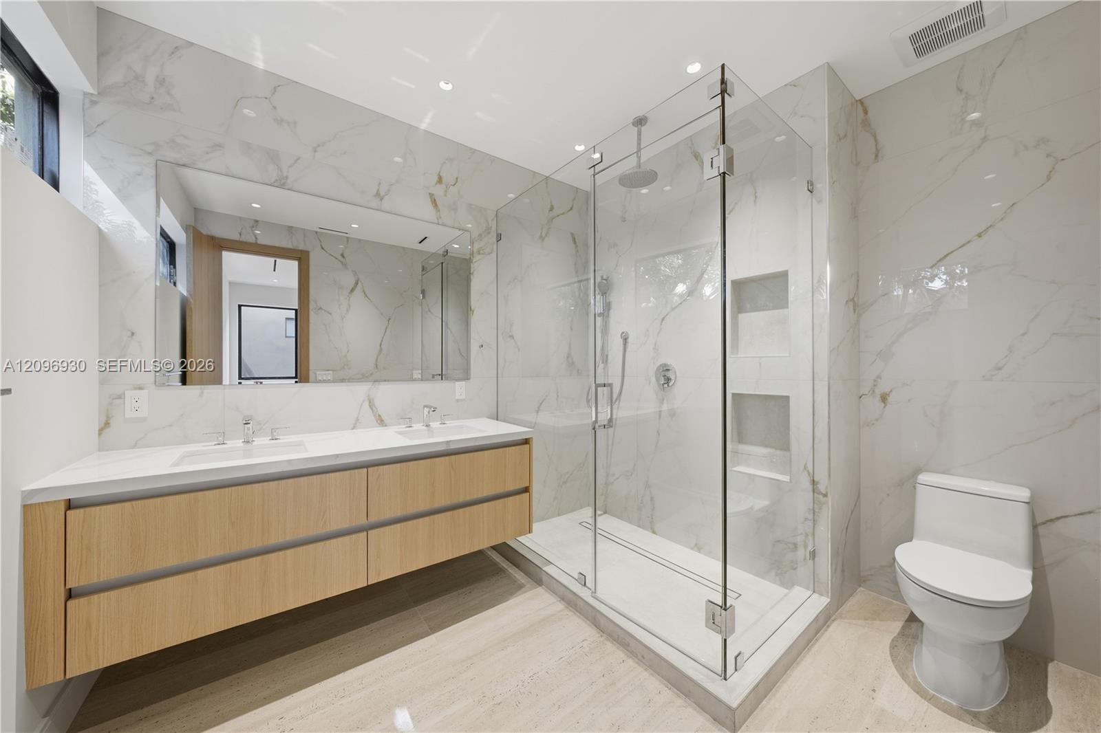 Modern bathroom with a floating wood double vanity and glass walk-in shower.