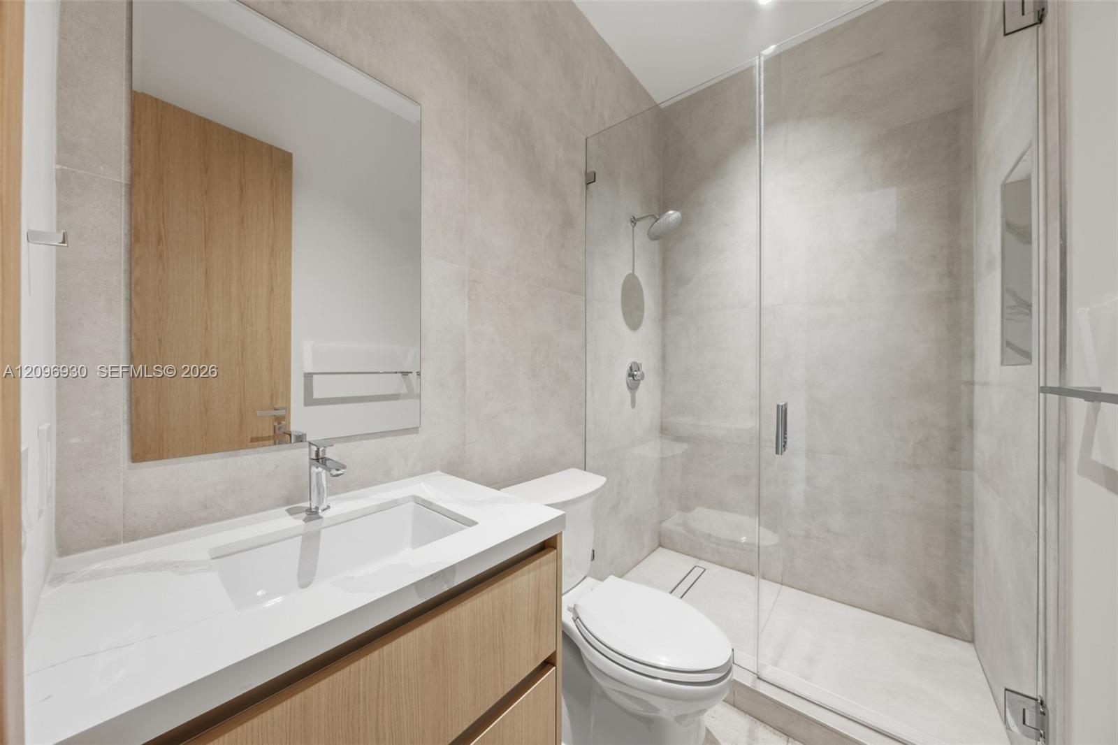 Modern bathroom with a glass walk-in shower and wood-front vanity.