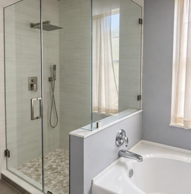 Bathroom with a glass-enclosed pebble-floor shower beside a white soaking tub.