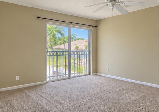 Vacant bedroom with beige carpet, ceiling fan, and sliding doors to a balcony.