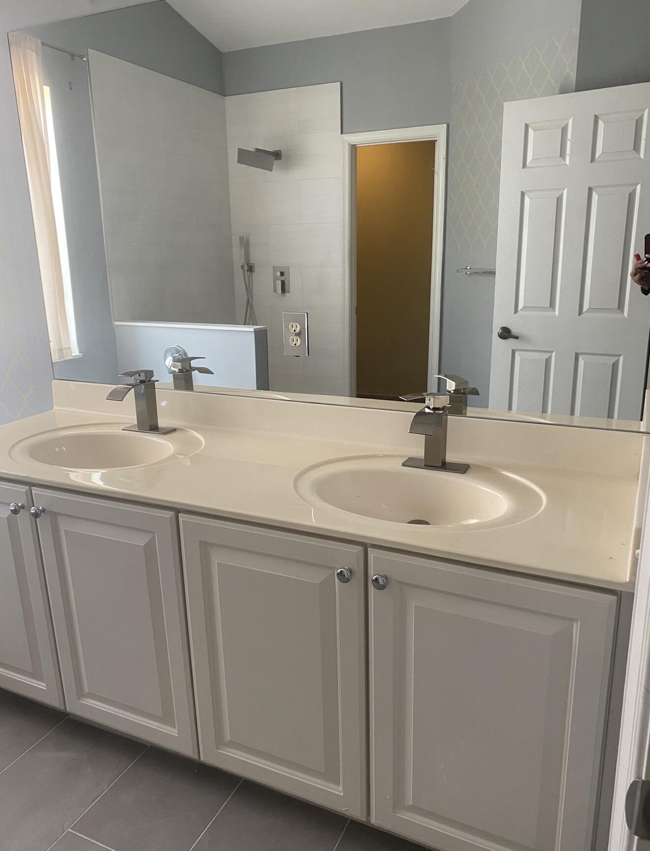 Bathroom with a double-sink vanity and tiled walk-in shower.