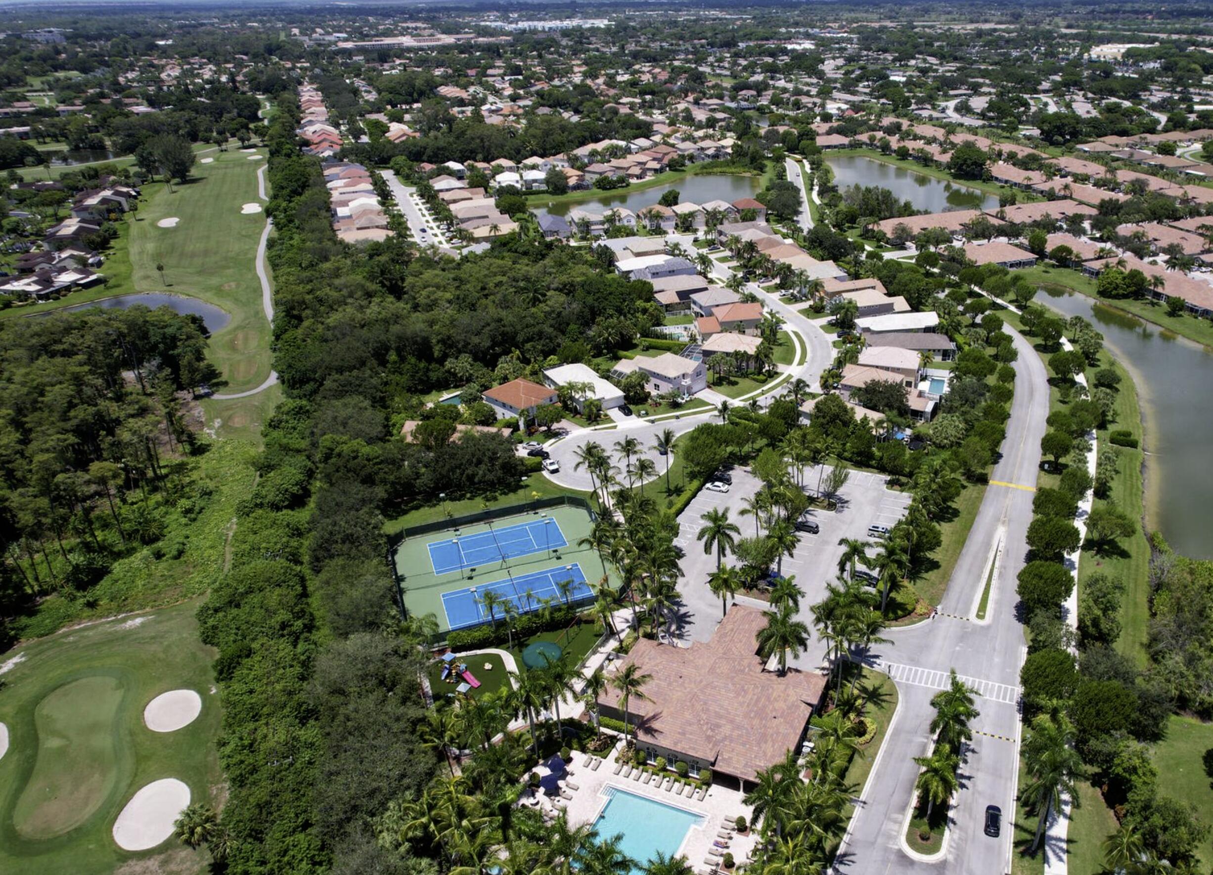 Aerial view of a residential community with a golf course, tennis courts, and pool.