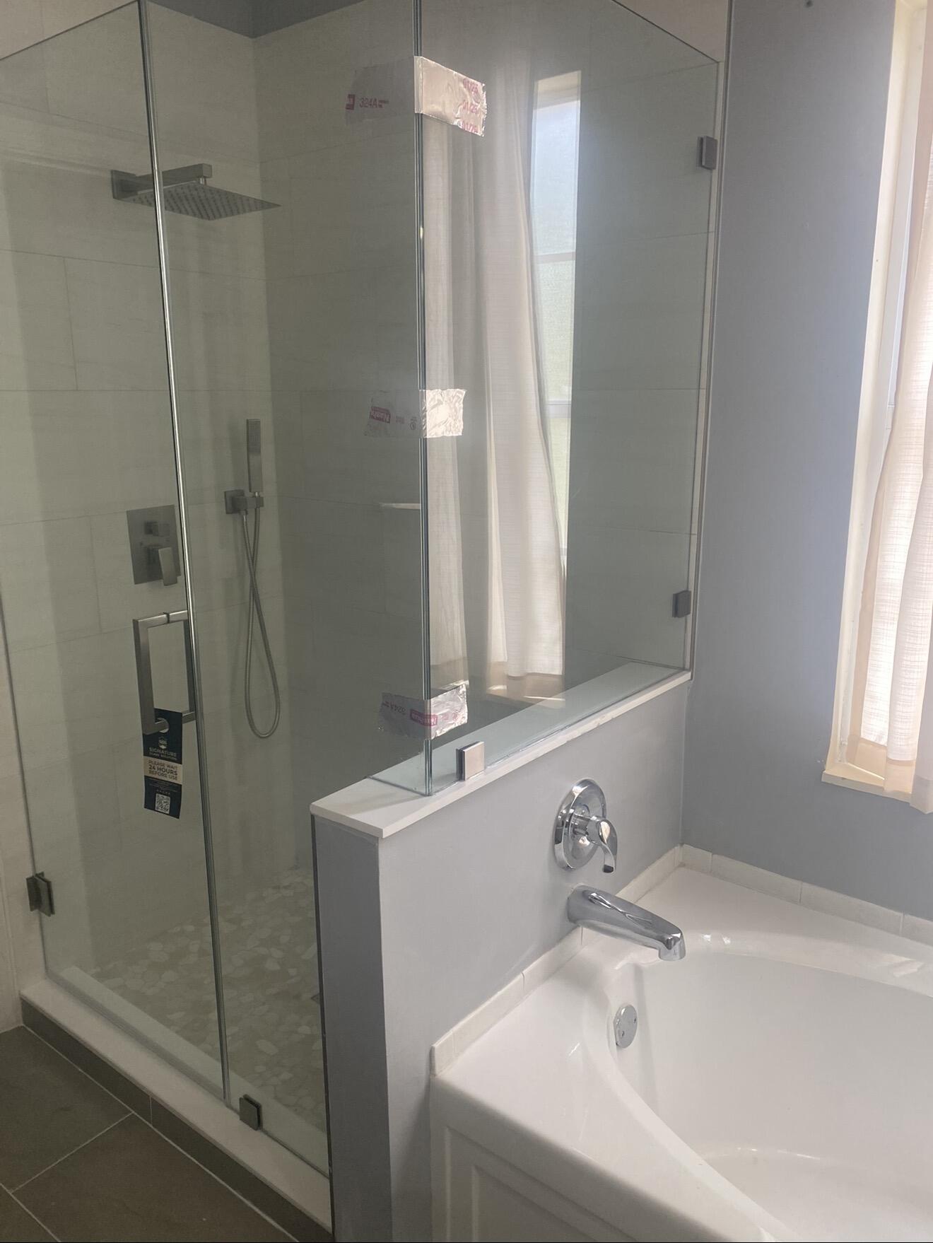 Bathroom with a white soaking tub beside a glass-enclosed shower with a rainfall showerhead.