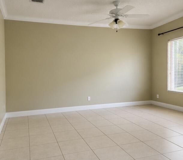 Empty room with beige walls, tiled floor, ceiling fan, and a window with white blinds.