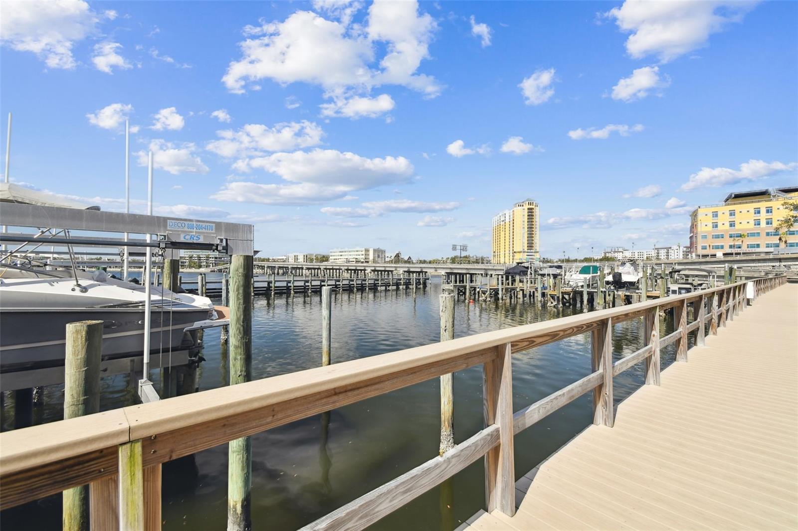 Marina boardwalk overlooking moored boats, calm water, and waterfront buildings.