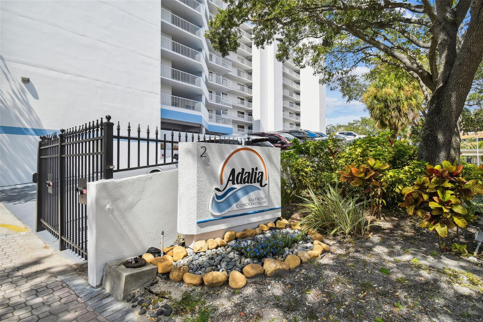 Adalia Bayfront Condominium exterior with its entrance sign, white balconies, and landscaped grounds.